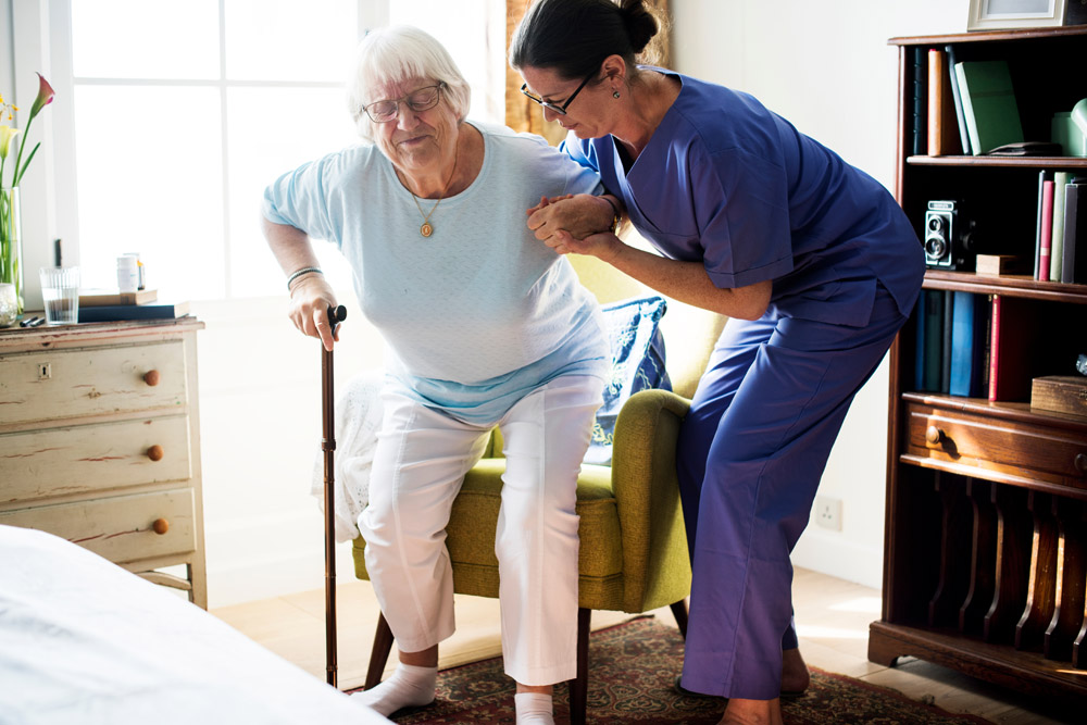 Nurse helping senior woman to stand in Williamsville, NY